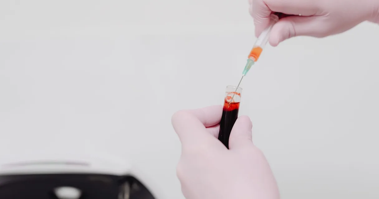 Mão com pipeta pingando sangue em um tubo de ensaio